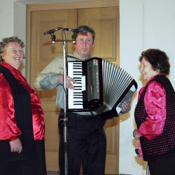 The Robnik sisters singing toasts accompanied by a musician.